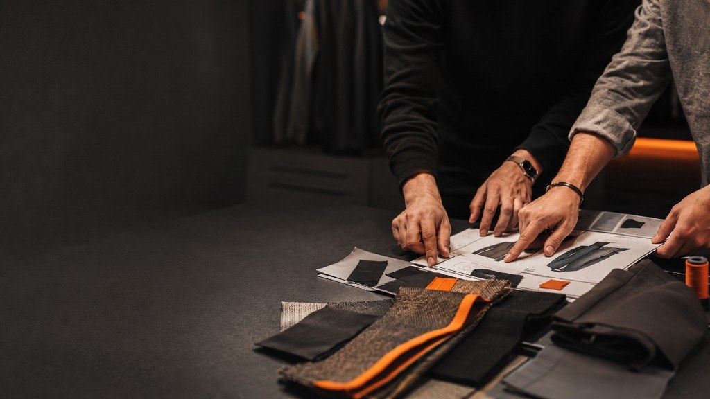 Two team members reviewing a tech pack and trims on the studio table
