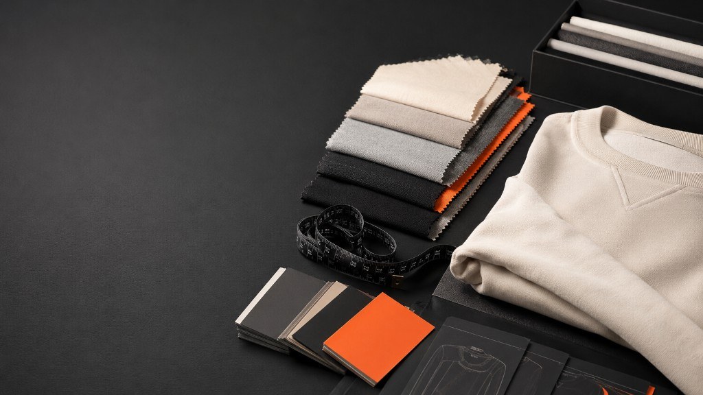 Fabric swatches and colour cards laid out beside a cream sweatshirt
